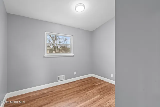 an empty room with wooden floor and window