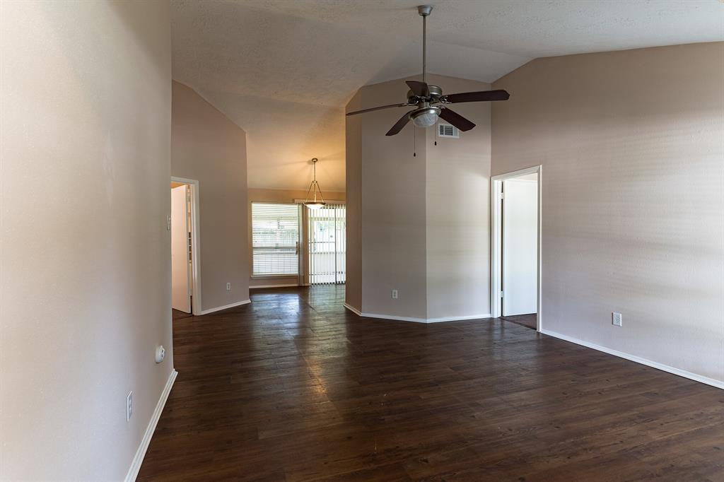 a view of empty room with wooden floor and ceiling fan