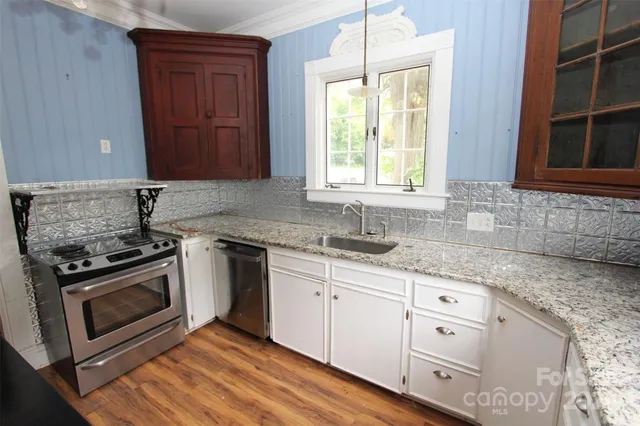 a kitchen with granite countertop a sink cabinets stainless steel appliances and a window