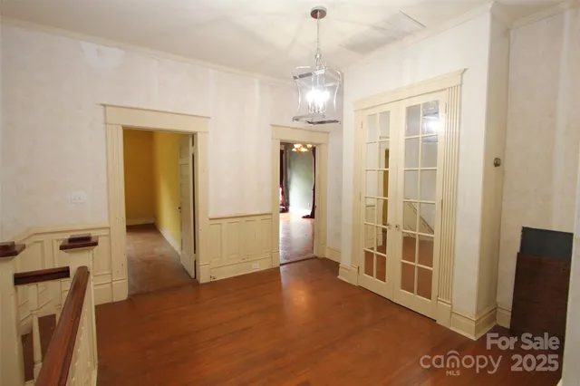 a view of a hallway with wooden floor and chandelier