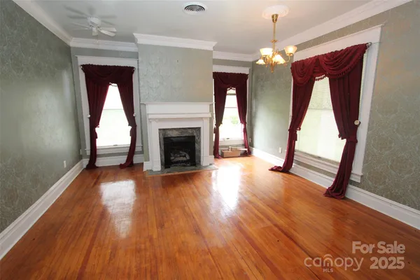 a view of an empty room with wooden floor fireplace and a window