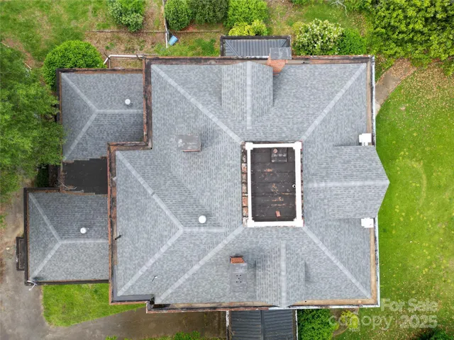 an aerial view of a house with a yard and large tree