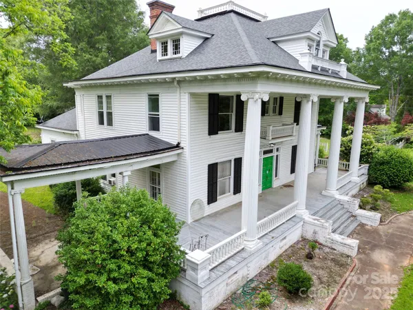 a view of a white house with large windows and plants