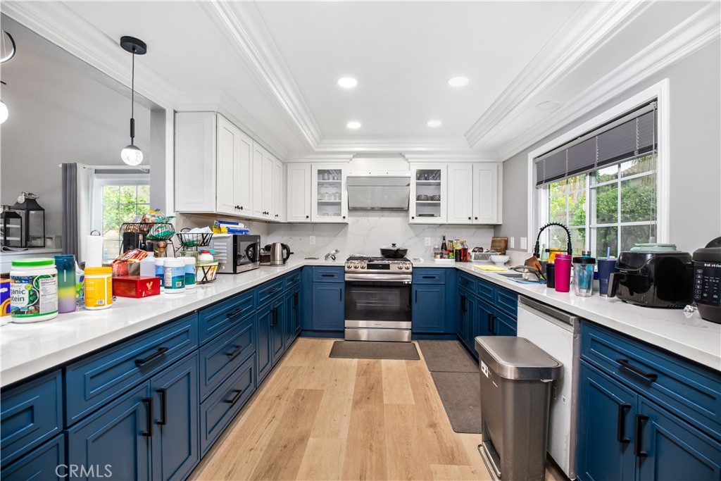 a kitchen with kitchen island granite countertop wooden floors stainless steel appliances a sink cabinets and a window