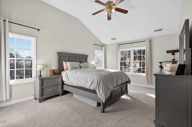 a spacious bedroom with a bed a dresser and a chandelier