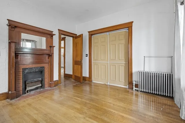 an empty room with wooden floor fireplace and windows