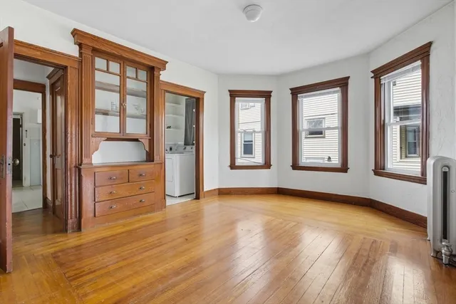 a view of an empty room with window and cabinet