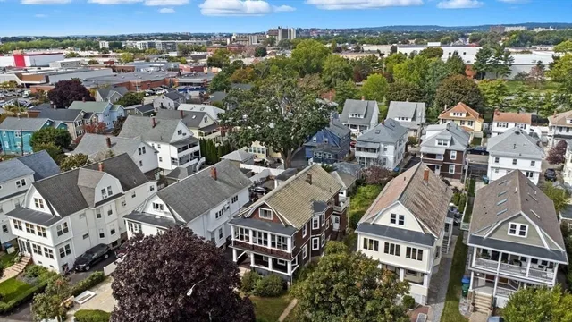 an aerial view of a residential apartment building with a yard and mountain view in back