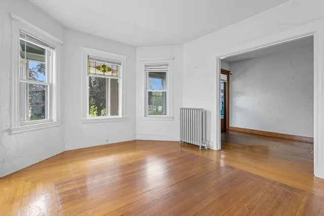 a view of an empty room with a window and wooden floor