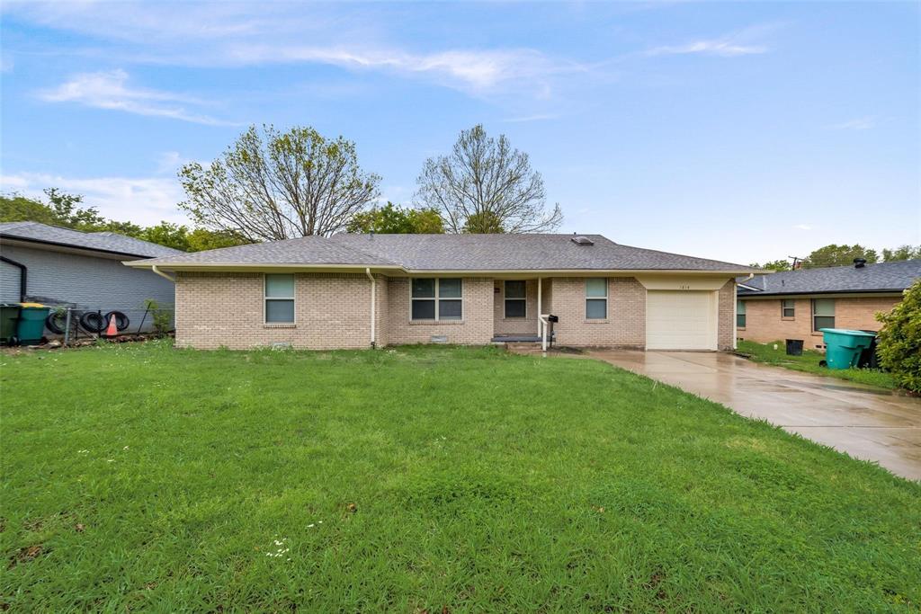 Ranch-style house with a front yard, concrete driveway, a garage, brick siding, and a shingled roof