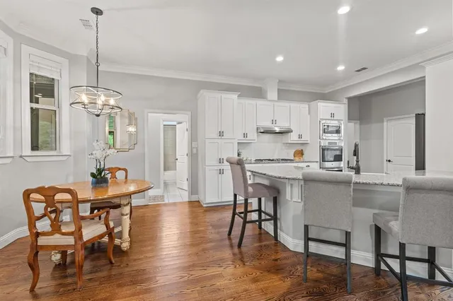 a dining room with stainless steel appliances kitchen island granite countertop a table chairs and a refrigerator