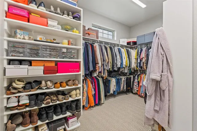 a view of walk in closet with clothes and shoes