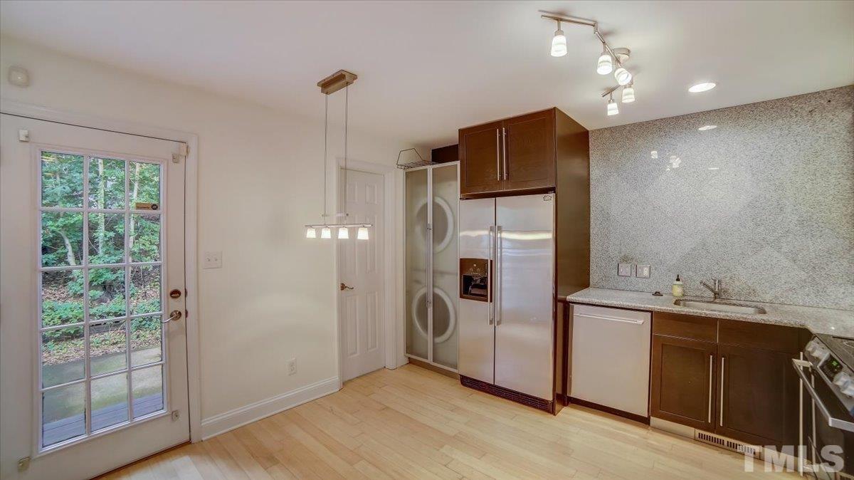 2504 Noble Road Raleigh, NC 27608 - Photo 9 of 28 a view of a kitchen with a sink and dishwasher a refrigerator with wooden floor