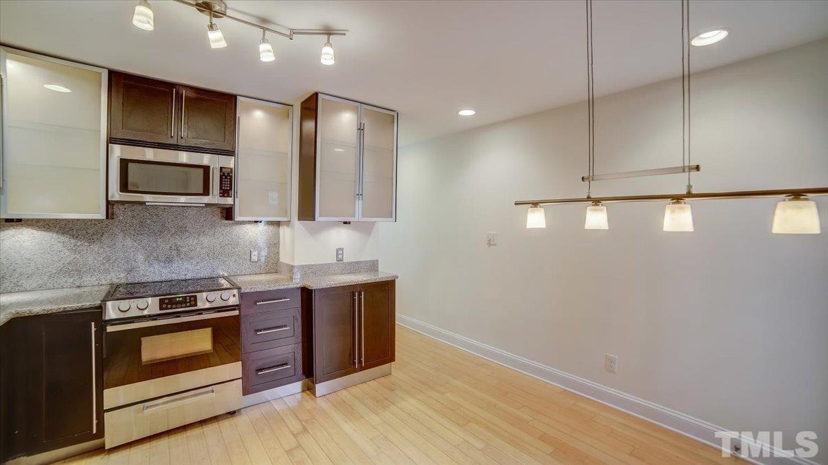2504 Noble Road Raleigh, NC 27608 - Photo 10 of 28 a kitchen with stainless steel appliances a stove a microwave and white cabinets