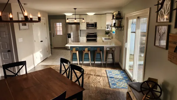 a kitchen with stainless steel appliances a dining table chairs refrigerator and microwave