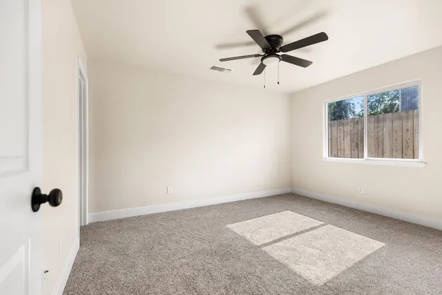 an empty room with a window and a ceiling fan
