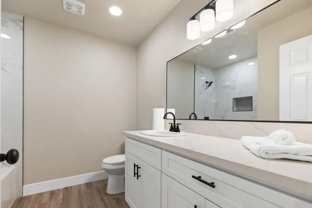 a bathroom with a granite countertop sink a toilet and a mirror