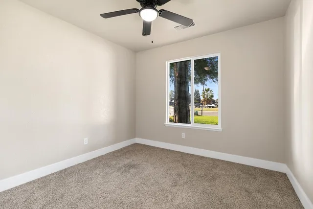 an empty room with a window and a fan