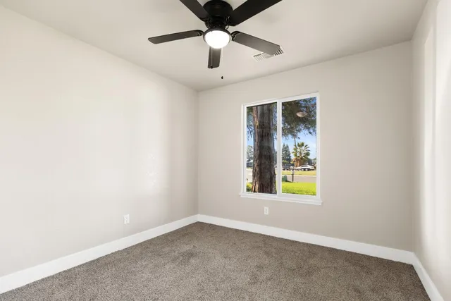 an empty room with window and ceiling fan