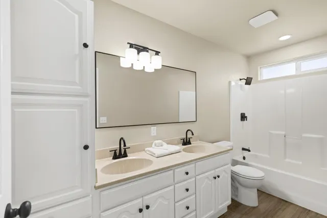 a bathroom with a double vanity sink toilet mirror and bathtub