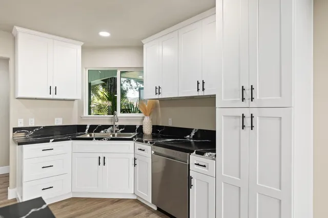 a kitchen with granite countertop a sink a stove and cabinets