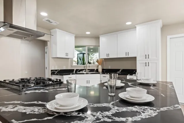 a kitchen with granite countertop a stove a sink and a stove