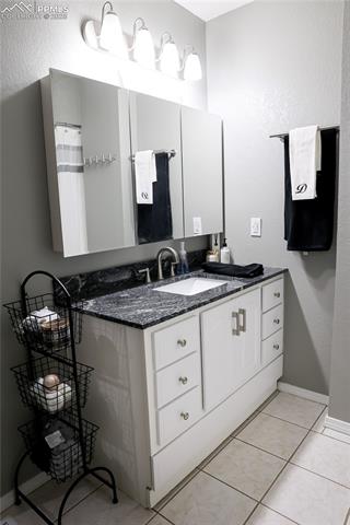 8115 Mustang Road Colorado Springs, CO 80908 - Photo 39 of 48 Full bathroom featuring vanity, a textured wall, light tile patterned floors, and a shower with shower curtain