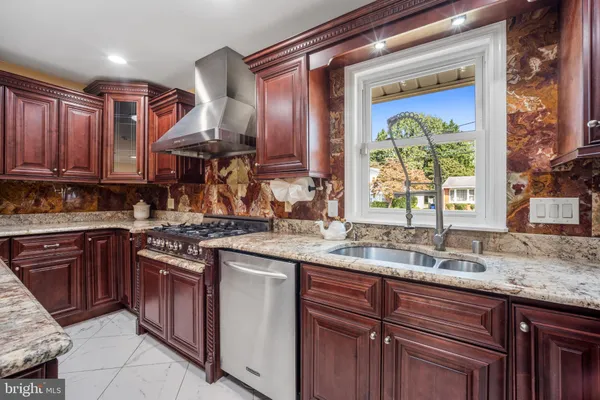 a kitchen with stainless steel appliances granite countertop a stove a sink dishwasher and a refrigerator with wooden cabinets