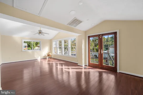 an empty room with wooden floor and ceiling fan
