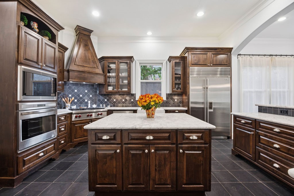 2508 Brun Street Houston, TX 77019 - Photo 16 of 50 Another angle of the kitchen featuring a spacious island with a marble countertop. The tile backsplash and flooring complement the elegant design, while ample natural light enhances the inviting atmosphere.