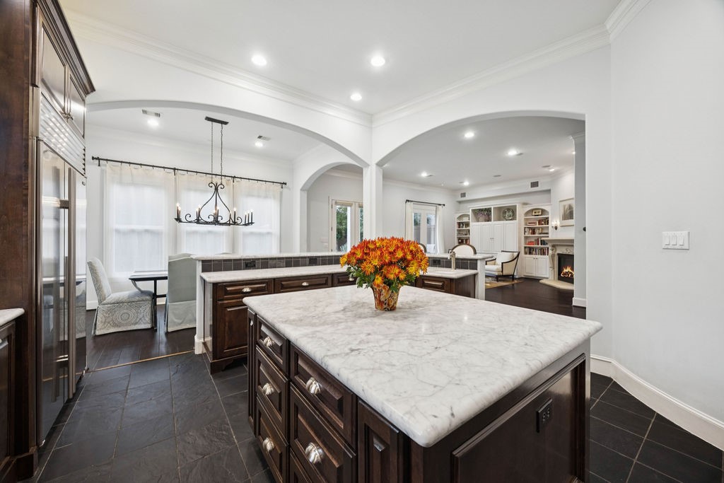 2508 Brun Street Houston, TX 77019 - Photo 17 of 50 This elegant kitchen features a large Carrera marble island. It opens to a cozy living area with a fireplace and built-in shelves, offering an inviting and functional living space.