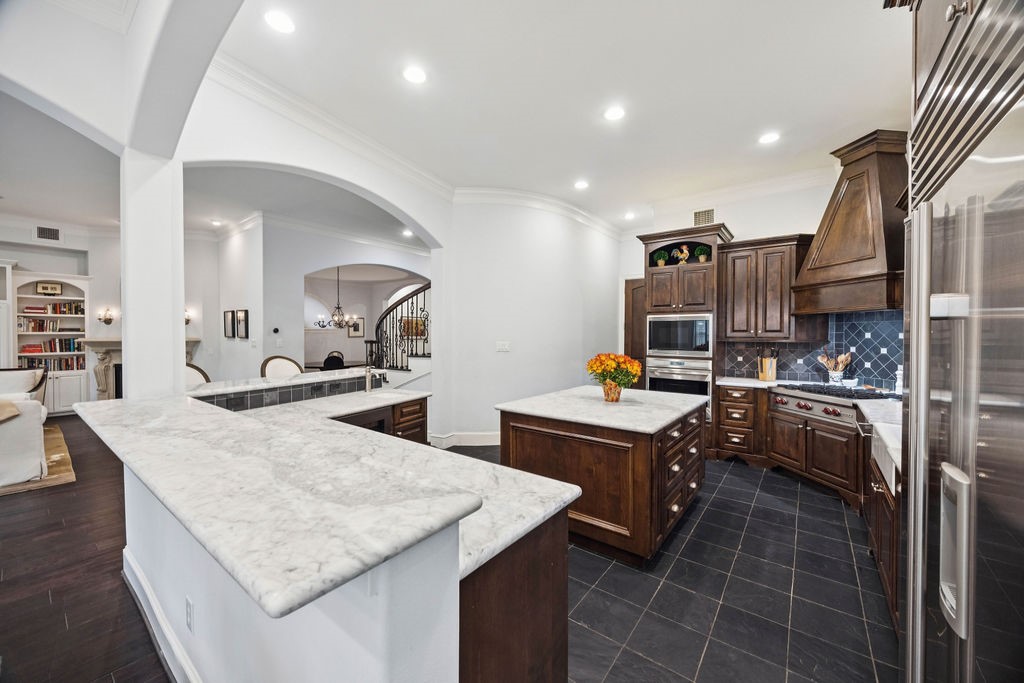 2508 Brun Street Houston, TX 77019 - Photo 18 of 50 This kitchen features a central Carrera marble island and countertops, and stainless steel appliances. The open layout connects to a cozy living area, creating a warm and inviting space.
