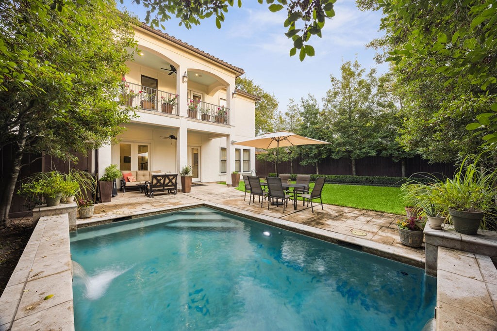 2508 Brun Street Houston, TX 77019 - Photo 25 of 50 This photo showcases a charming two-story home with a spacious backyard featuring a swimming pool, patio dining area with an umbrella, and lush greenery, perfect for outdoor relaxation and entertaining.