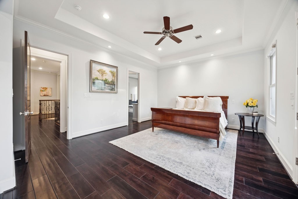 2508 Brun Street Houston, TX 77019 - Photo 28 of 50 This spacious primary bedroom features elegant dark hardwood floors, a tray ceiling with recessed lighting, and a ceiling fan. It has ample natural light from the windows.