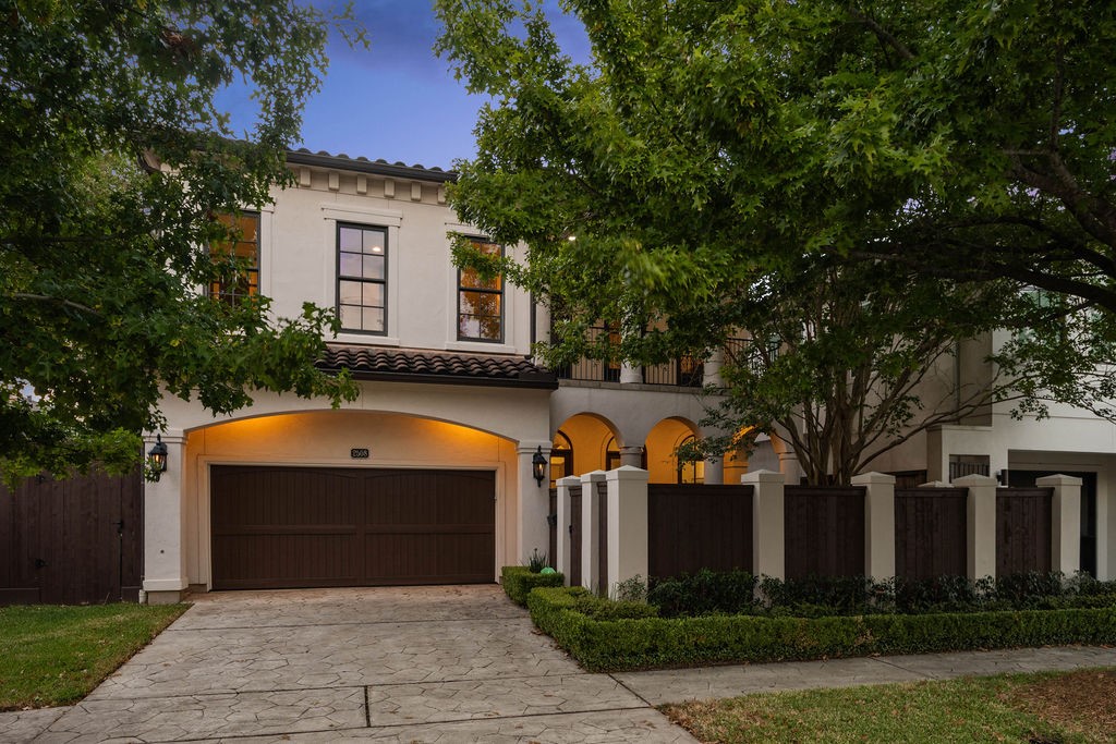 2508 Brun Street Houston, TX 77019 - Photo 49 of 50 This charming two-story home features a Mediterranean-style facade with a tiled roof, arched entryway, and a spacious two-car garage. The well-maintained front yard is framed by mature trees and a decorative fence, offering both privacy and curb appeal.