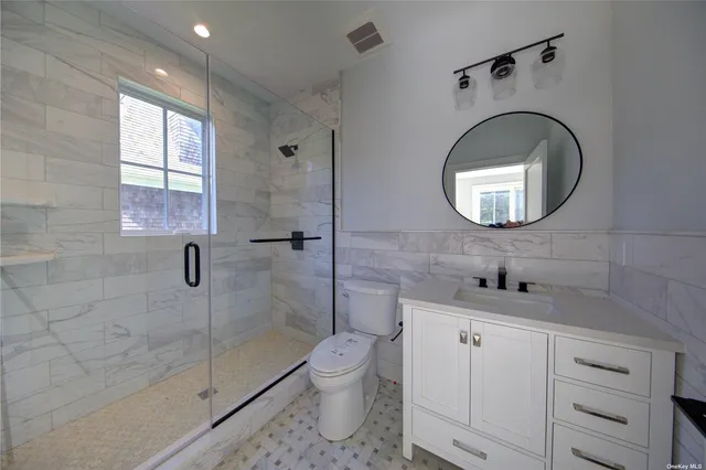 a bathroom with a toilet sink a mirror and shower