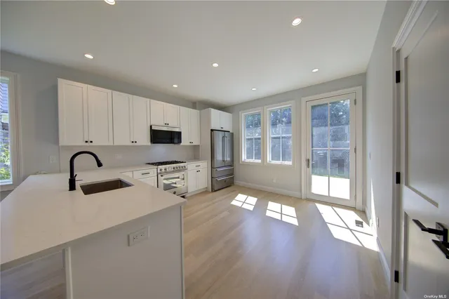 a kitchen with stainless steel appliances granite countertop a refrigerator oven a sink dishwasher and white cabinets with wooden floor