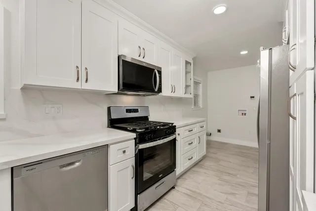 a kitchen with white cabinets stainless steel appliances and sink
