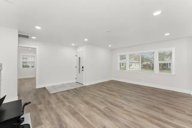 an empty room with wooden floor ceiling fan and windows
