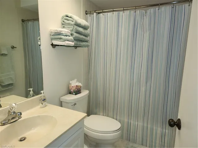 a bathroom with a sink a toilet and shower curtain