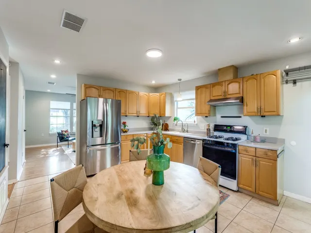 a kitchen with stainless steel appliances kitchen island granite countertop a refrigerator a stove a sink a dining table and chairs