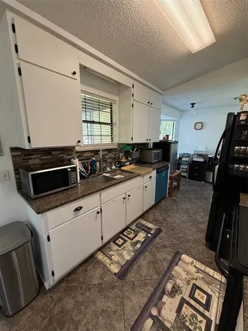 a kitchen with granite countertop a stove sink and cabinets