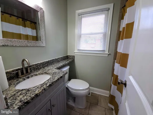 a bathroom with a granite countertop toilet sink and mirror