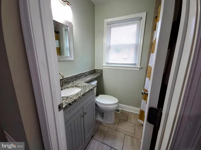 a bathroom with a granite countertop toilet and a sink