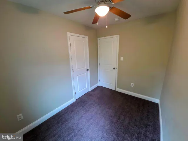 an empty room with a chandelier fan and wooden floor