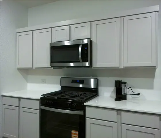a kitchen with stainless steel appliances granite countertop white cabinets and a stove top oven