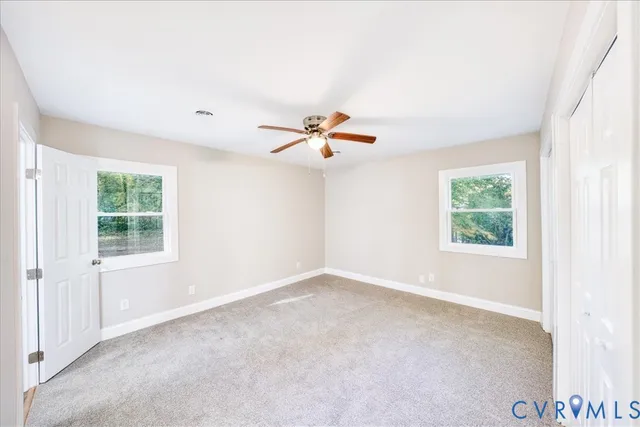 an empty room with window and ceiling fan