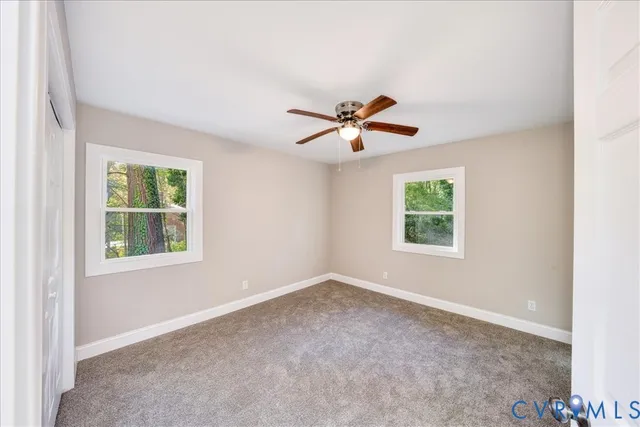 an empty room with windows and ceiling fan