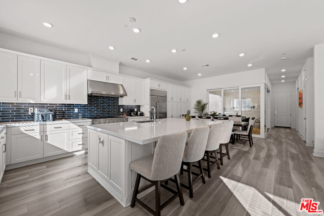 26710 Beartown Lane Stevenson Ranch, CA 91381 - Photo 4 of 21 a large white dining hall with stainless steel appliances granite countertop a stove a sink a dining table chairs and view kitchen