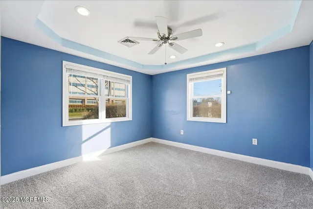 an empty room with windows and fan